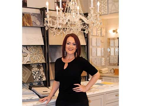 A woman in a black dress posing for a photo near a display of tile samples